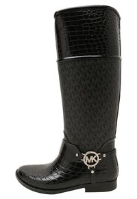 Bota negra hasta la rodilla con textura de cocodrilo en la punta y parte superior negra brillante. Presenta un tejido mate contrastante con un cinturón de logotipo de MK.