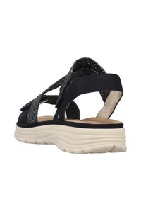 Svart och grå sandal med en strukturerad remdesign, justerbar stängning, mjukt innerfoder och en tjock vit sula.