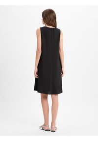 Zwarte mouwloze jurk met een ronde halslijn en een keyhole knoopsluiting aan de achterkant. Losse pasvorm, middellange lengte, gemaakt van lichtgewicht stof.