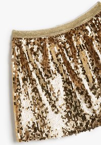 Falda de lentejuelas doradas con cintura elástica, que presenta una superficie brillante de discos metálicos en diferentes tonos de dorado y crema.