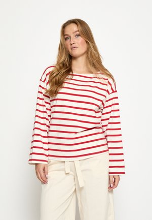 Rood-wit gestreept shirt met lange mouwen en een boothals, een losse pasvorm en zachte stof. Gecombineerd met lichtgekleurde, loszittende broek.