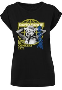Schwarzes T-Shirt mit einem Grafikmotiv von David Bowie in Konzertaufführung, mit dem Text "DAVID BOWIE LIVE IN CONCERT 1973" und einem gelben Globusdesign.