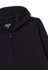 Felpa nera con zip realizzata in tessuto morbido, dotata di cappuccio con coulisse, cuciture minime e un piccolo etichetta con la scritta "essentials" all'interno.