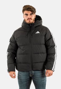 Chaqueta de plumas negra con capucha, que presenta costuras horizontales, cierre de cremallera y franjas laterales blancas. El tejido parece suave y ligero.