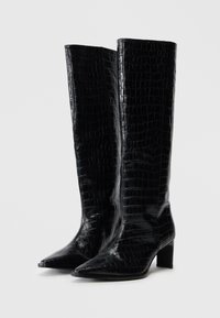 Μαύρες μπότες μέχρι το γόνατο με γυαλιστερή υφή κροκοδείλου, μυτερή μύτη και τακούνι τύπου block, με κομψό σχεδιασμό και ομαλή επιφάνεια.