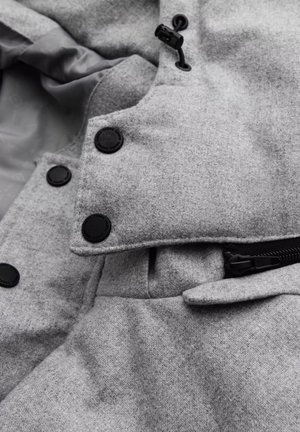 Gray wool-blend jacket featuring a textured fabric, black buttons, a zip closure, and a side flap pocket design.