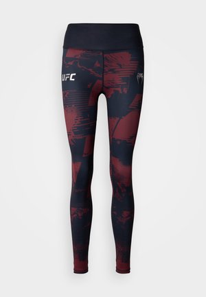 Tajice tamnoplave i bordo boje s apstraktnim uzorcima. Imaju visok pojas i bijeli logo "UFC" na lijevom bedr.