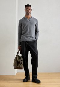 Gray wool blend pullover with a collar, black trousers, and black shoes. Carrying an olive green bag with leather accents.