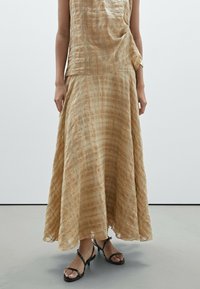 Beige, gemusterter langer Rock und Oberteil aus leichtem Stoff. Der Rock hat ein fließendes Design mit einer subtilen Karotextur und einem Saumdetail.