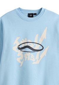 Felpa azzurra chiara in cotone, con un grande design grafico nero e beige sul davanti, caratterizzato da forme astratte e testo.