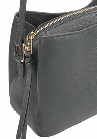 Grijze leren crossbody tas met een gestructureerde afwerking, goudkleurige rits en een verstelbare schouderband. Compacte vorm met een minimalistisch ontwerp.
