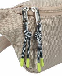 Borsa in tessuto beige con superficie testurizzata, dotata di zip argentate e lacci a schemo nero e bianco con punte verdi.