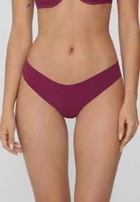 Bas de bikini bordeaux avec une texture lisse, une taille basse et une couverture minimale, doté d'une taille sans couture et de lignes épurées.