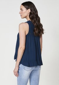 Blusa senza maniche di colore blu navy con orlo arricciato e dettagli delicati sulle spalle, realizzata in tessuto leggero e dal fit morbido.
