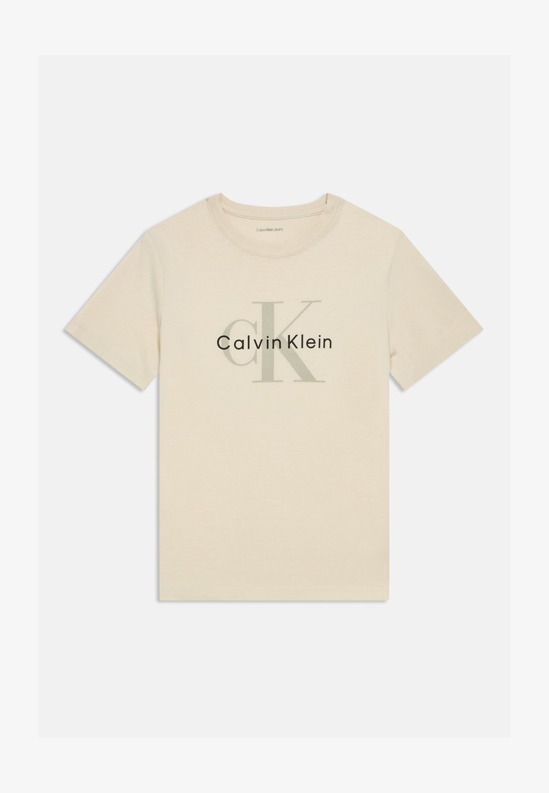 Beige színű pamut póló kerek nyakkal. A "CK" és a "Calvin Klein" nagyméretű szürke nyomtatással látható rajta. Rövid ujjú.