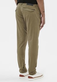 Chinos kaki avec cinq poches, coupe droite et lignes épurées. Tissu doux avec un léger éclat et longueur aux chevilles.