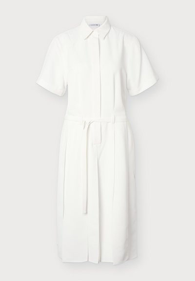 Robe chemise midi blanche à manches courtes avec col et ceinture amovible à la taille, avec patte de boutonnage frontale cachée.