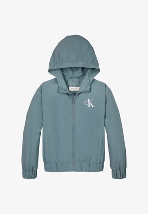 Chaqueta ligera con capucha en suave tela azul, con puños elásticos, bolsillos frontales y un logo blanco en el pecho, que presenta un cierre de cremallera.
