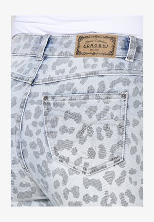 Jean en denim à imprimé léopard bleu clair, avec une étiquette en cuir à la taille et une poche arrière ornée d'une seule rivet en métal.
