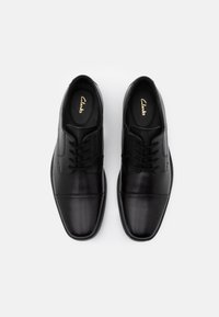 Black leather dress shoes with a smooth finish, lace-up design, and subtle stitching details. Rounded toe and cushioned interior.