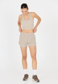 Beige Sport-BH und passende Shorts mit elastischem Bund. Weicher, leichter Stoff; betont das Design der lässigen Sportbekleidung.