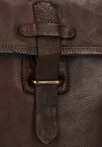 Bruine leren tas met een gestructureerd oppervlak, gestikte randen, een gespsluiting en een metalen accentlus om de klep te bevestigen.