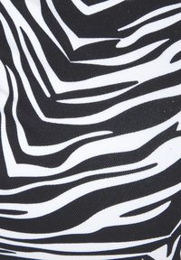 Tessuto in bianco e nero caratterizzato da un motivo astratto a strisce di zebre; texture liscia con una finitura lucida, che enfatizza colori audaci e contrastanti.