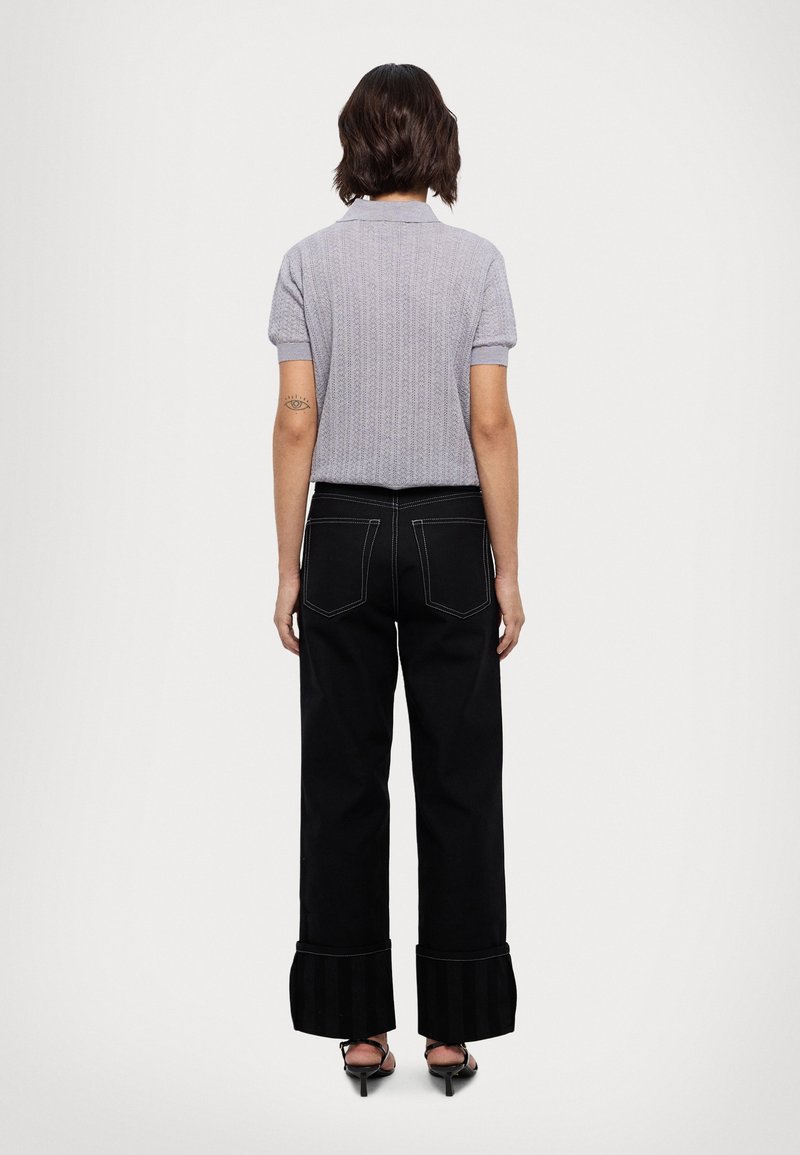 Polo grigio a maniche corte con motivo testurizzato, pantaloni neri a gamba larga con polsini a righe e sandali con tacco alto.