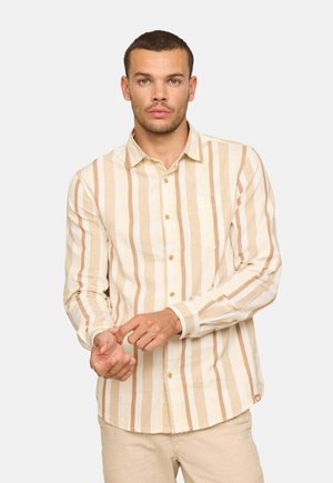 Chemise à manches longues rayée en coton crème et beige. Comprend une patte de boutonnage sur le devant, une petite poche poitrine et un ourlet arrondi. Le modèle ajuste sa manche au poignet.