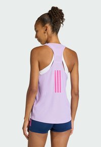 Svijetloplavi sportski top s racerback dizajnom, s tri ružičaste pruge na leđima. Uparen s tamnoplavim kratkim hlačama.