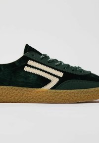 Sneaker verde in velluto con suola in gomma testurizzata. Presentano un design a zig zag crema e lacci coordinati. Punta arrotondata e profilo basso.