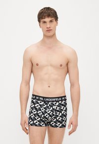 Melni kokvilnas bokseršorti ar atkārtotu baltu grafisko rakstu un zīmola jostu. Gluda tekstūra, pieguļošs dizains.