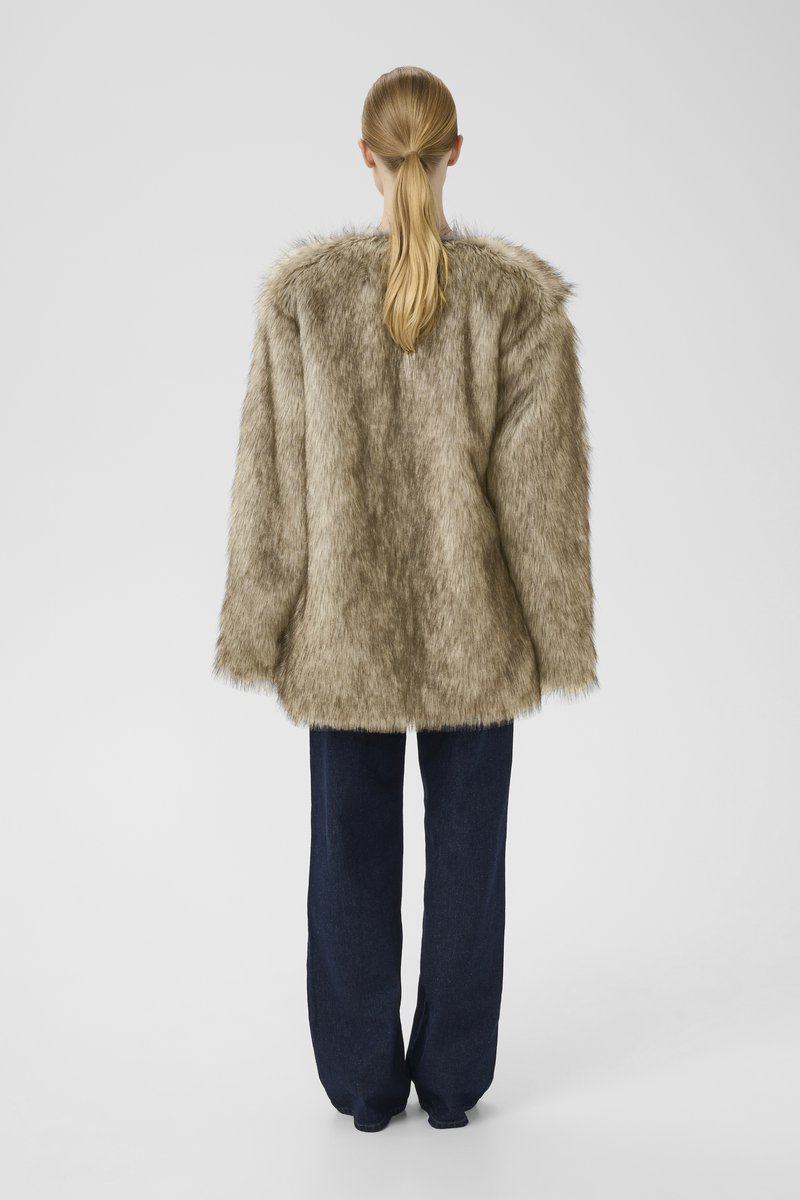 Faux-Fur-Mantel in Hellbraun mit weicher Textur und weiter Schnittführung, kombiniert mit dunkelblauen, lässig geschnittenen Jeans.