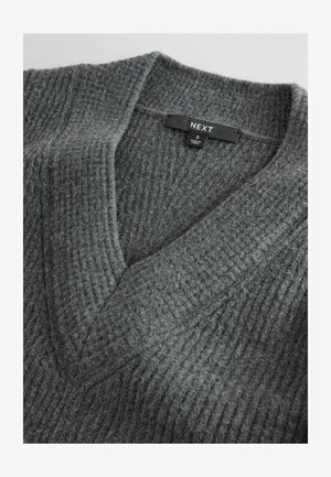 Sivý pletený sveter s výstrihom do V a rebrovanou textúrou. Tkanina vyzerá mäkko a pohodlne, s etiketou zobrazujúcou "NEXT" a veľkosť "S."