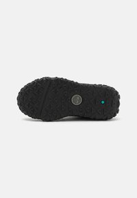 Suola di scarpa in gomma nera con una texture pronunciata e un motivo di battistrada evidente, dotata di un logo circolare al centro. Presenta un accento turchese.