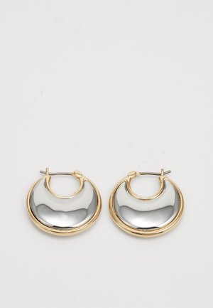 Pair of crescent-shaped hoop earrings with smooth silver-tone centers and gold-tone edges on a light background.