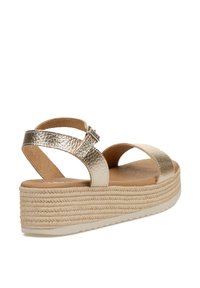 Sandalia cuña metálica dorada con dos correas anchas sobre el pie, hebilla ajustable en el tobillo y plataforma texturizada estilo cuerda.