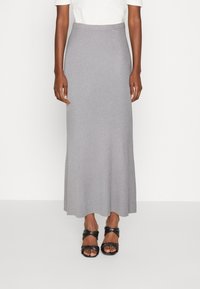Falda maxi de punto acanalado gris con cintura ajustada y dobladillo fluido, combinada con sandalias negras de tiras retorcidas.
