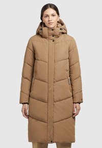 Bēšas puffer jaka ar augstu apkakli, ar rāvējslēdzēju un pogu aizdari, diognālām quiltēšanas līnijām un sānu kabatām.