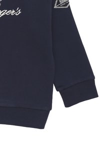 Felpa blu navy con polsini e orlo a coste, con testo ricamato bianco sul davanti e un patch del logo sulla manica.