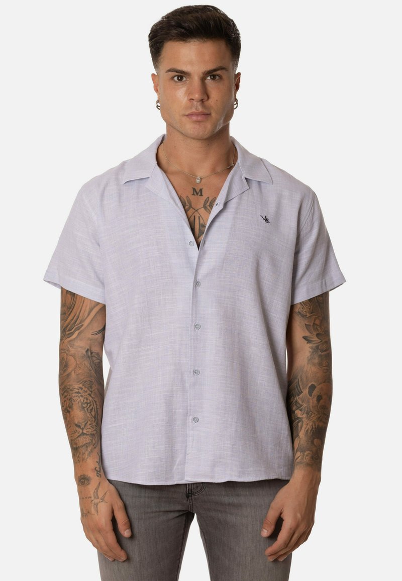 Camisa de manga corta, abotonada, en un suave color lavanda, de tejido texturizado, con cuello y pequeño detalle de logo en el lado izquierdo del pecho.