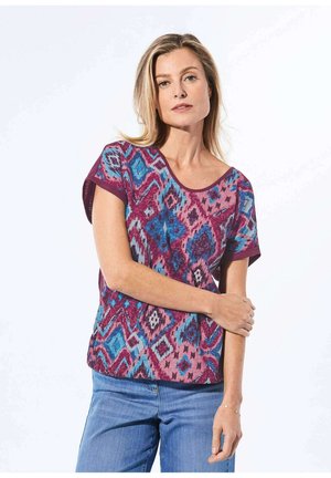 T-shirt à manches courtes en violet, bleu et magenta avec un motif géométrique. Encolure ronde, tissu doux et coupe décontractée.
