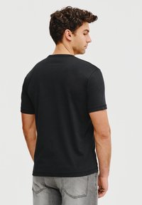 Czarny bawełniany t-shirt z krótkimi rękawami, okrągłym dekoltem i gładkimi szwami. Widok z tyłu ukazuje gładką fakturę i swobodny krój.