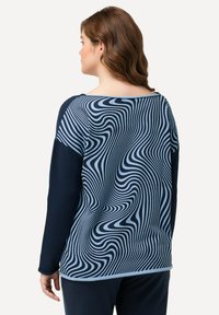 Maglietta a maniche lunghe con un motivo ondulato blu e navy, realizzata in tessuto morbido, con scollatura ampia e vestibilità comoda.