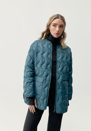 Chaqueta acolchada en verde azulado con cremallera frontal, dos bolsillos delanteros y cuello alzado, hecha de un material brillante con una textura suave.