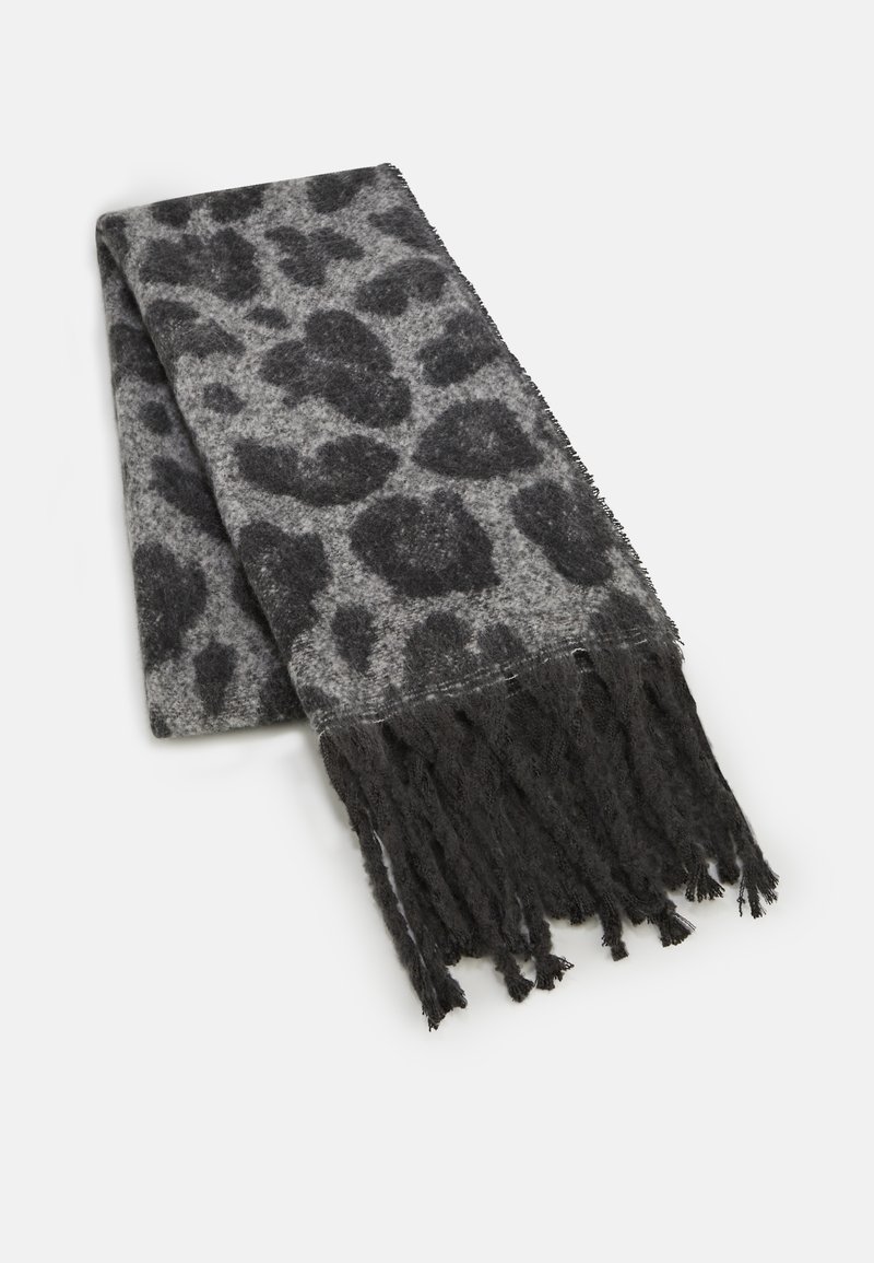 Écharpe en laine douce avec un motif léopard gris foncé et de longues franges noires, pliée sur un fond blanc.