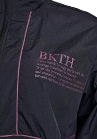 Melnā vieglā jaka ar teksturētu virsmu, rozā akcentiem un "BKTH" uzrakstu, kā arī motivējošu tekstu priekšpusē.