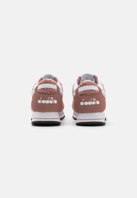Sneaker in suede rosa con dettagli bianchi, parte posteriore morbida, suola in gomma nera a contrasto e logo del marchio ben visibile sul tallone.