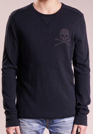 Langärmeliges marineblaues Hemd aus einem weichen Stoff, mit einem dezenten Totenkopf- und Knochen-Design auf der Brust, rohen Kanten an den Nähten und einem Rundhalsausschnitt.