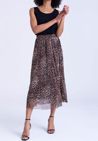 Leopardmønstret midi-nederdel med en gennemskinnelig tekstur, der har en elastisk talje. Sat sammen med en sort ærmeløs top og sorte strophæle.